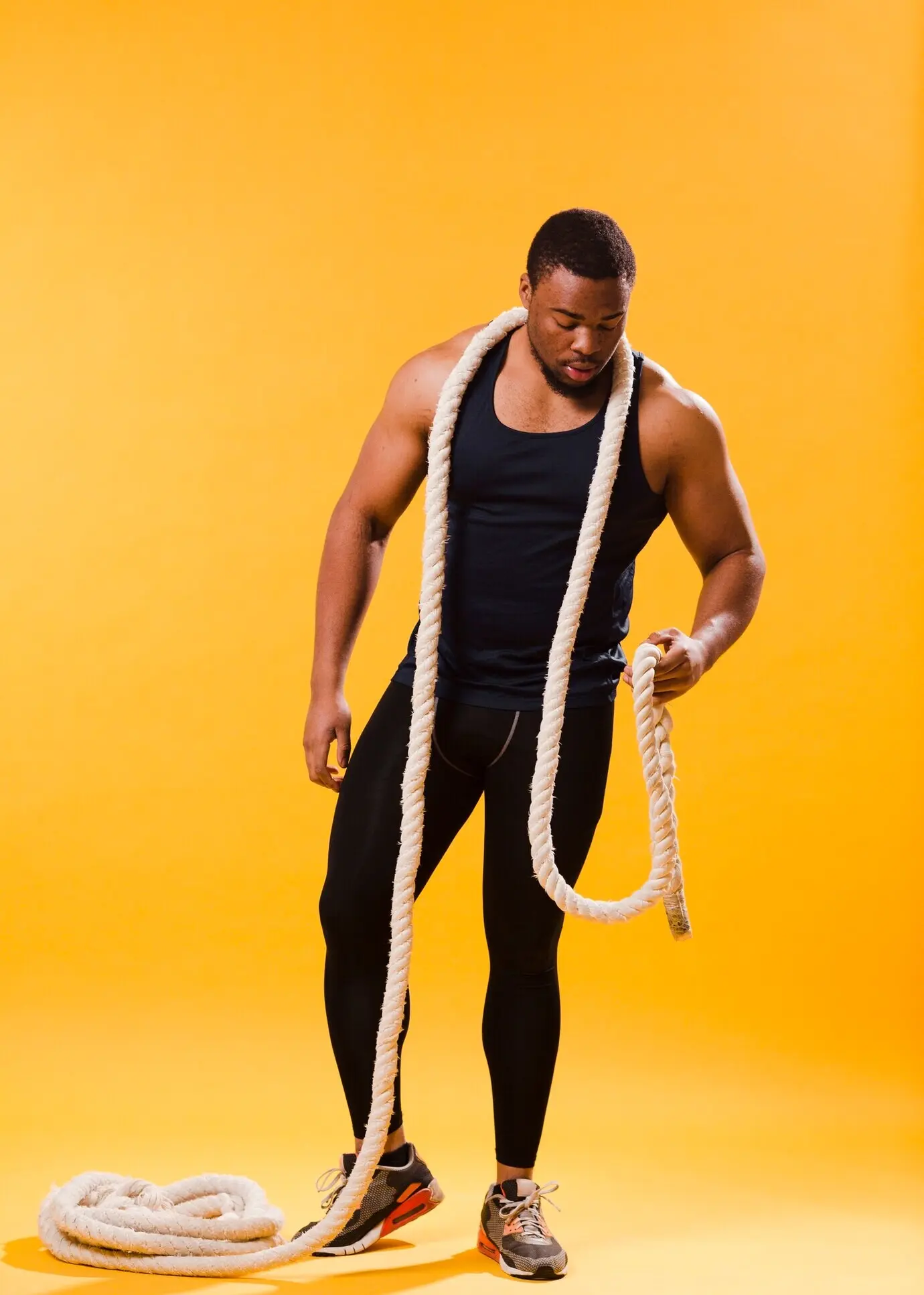 Vista frontal de un hombre musculoso con ropa de gimnasio y una cuerda.